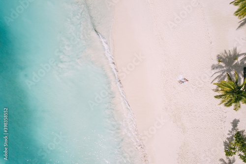 A couple lies on the beach on the white sand. Aerial shoot by drone © kumantsova