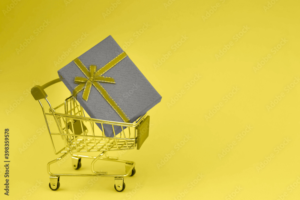 Colors yellow and gray , Color of the year of 2021 Illuminating , Ultimate Gray. Mini supermarket cart with gift box in trendy colors 2021.