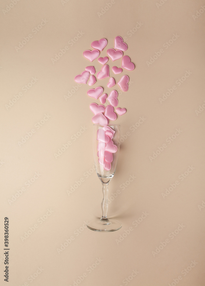 .Wine glass with pink hearts on a beige background. Flat composition, top view. Valentine's Day. Romantic. Wedding.