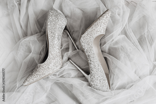 pair female pointy-nosed silver shining holiday shoes on Ultimate Gray color tulle fabric, holiday layout, selective focus