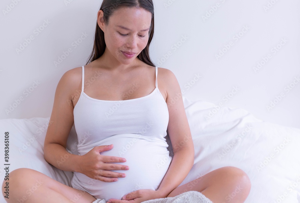 A pregnant woman holding her baby belly at home. Maternity love and motherhood.