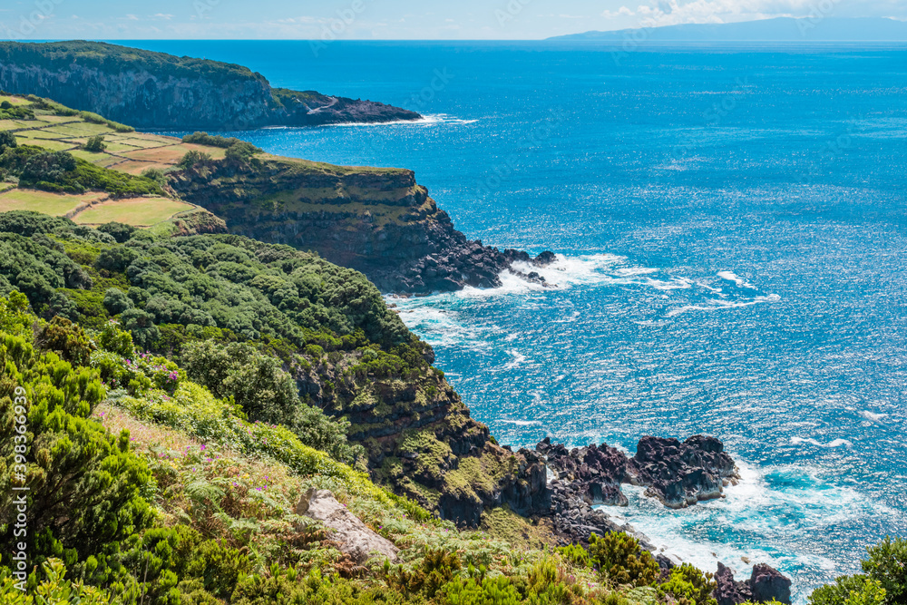 Hiking on cliffs with vegetation next to the turquoise water Atlantic Ocean in Terceira, Azores PORTUGAL