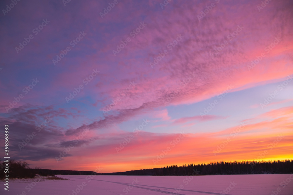 Sunset winter landscape with snow-covered road in violet and pink colors