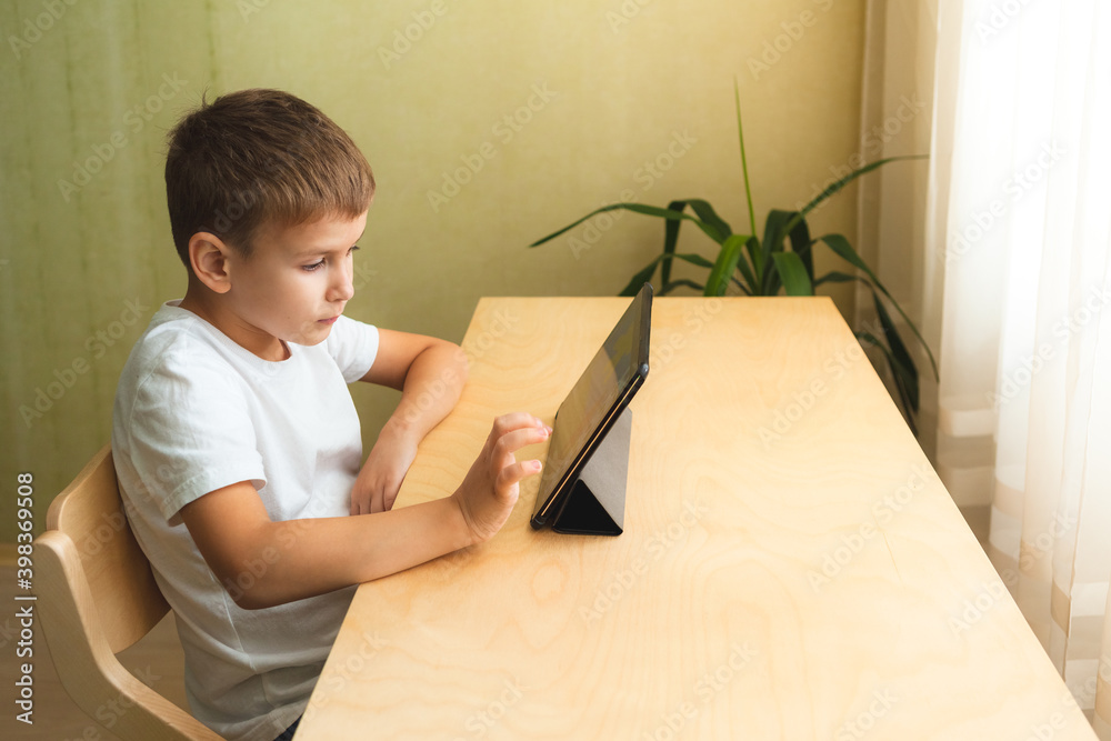 Happy boy doing homework with laptop at home. Child using gadgets for study. Education and distance learning concept Happy boy doing homework with laptop at home. Child using gadgets for study. Education and distance learning concept