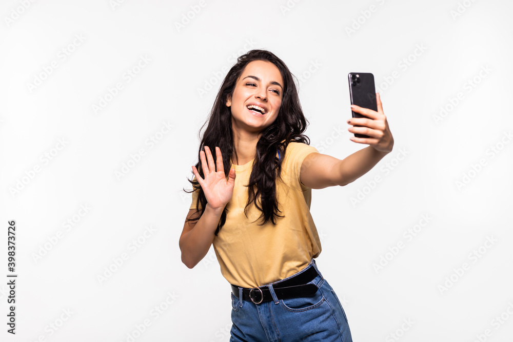 Smiling young woman making selfie photo while waving palm isolated on a white background Smiling young woman making selfie photo while waving palm isolated on a white background
