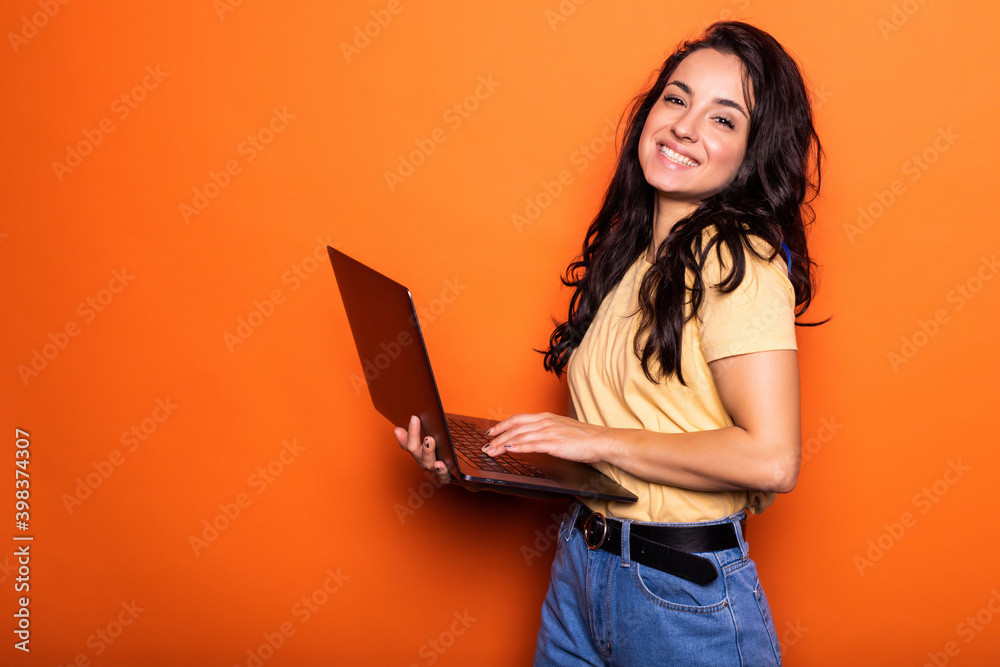Smiling young blonde woman holding laptop posing isolated on yellow orange background. People lifestyle concept. - obrazy, fototapety, plakaty 