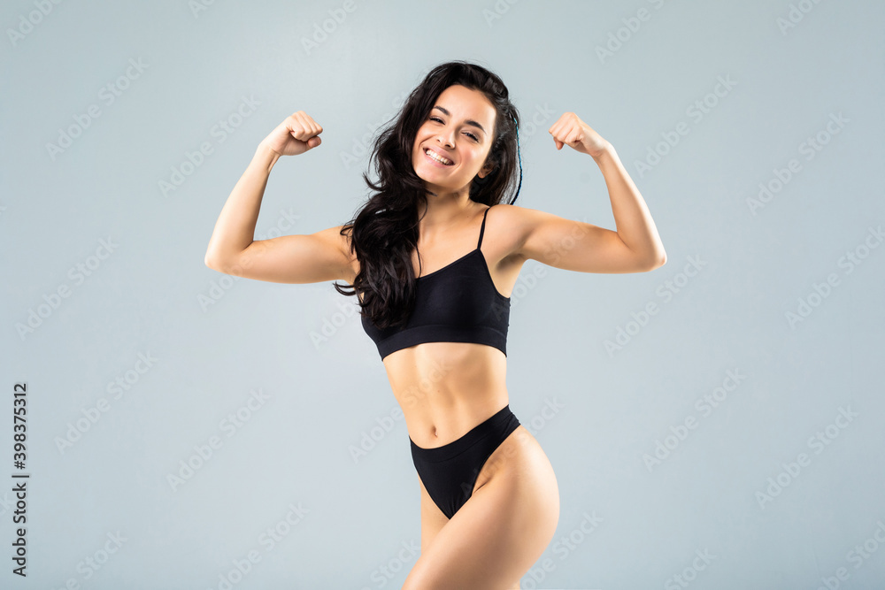 Sport fitness woman flexing show her biceps muscles, young smile girl athletic body, perfect figure wear black panties isolated over white background