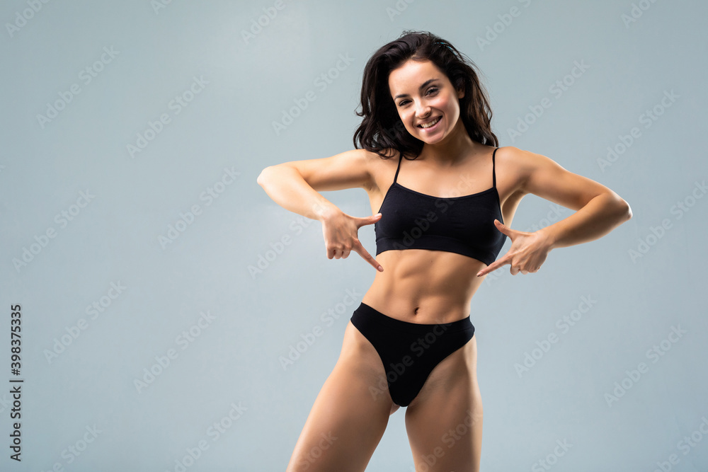 Young, sporty, fit and beautiful woman with sexy body over grey background.