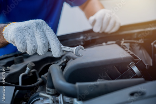 Auto mechanic holding wrench prepair to car service care. Car open the bonnet to checking engine and service. © Chanakon