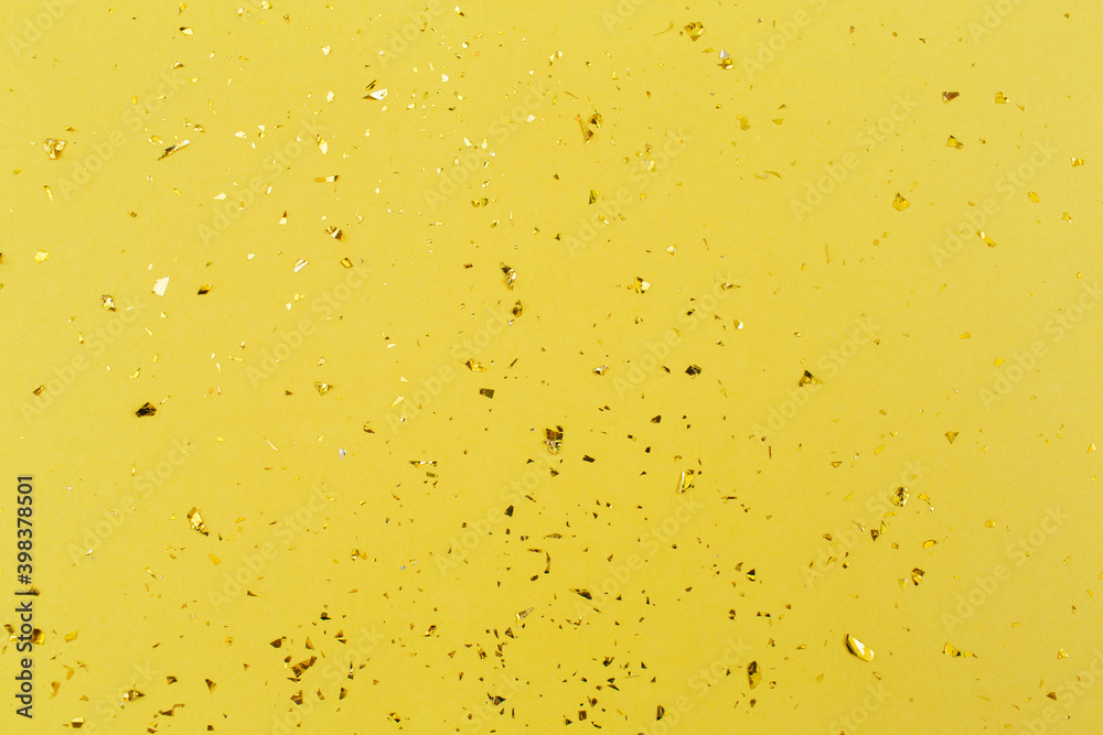 Gold confetti on yellow paper background. Festive holiday backdrop. Birthday congratulations Christmas New Year. Flat lay, top view, copy space. Gold confetti on yellow paper background. Festive holiday backdrop. Birthday congratulations Christmas New Year. Flat lay, top view, copy space.