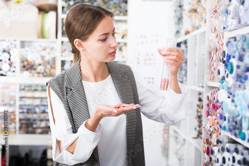 Portrait of young attractive woman choosing buttons for clothes in needlecraft store.. photo