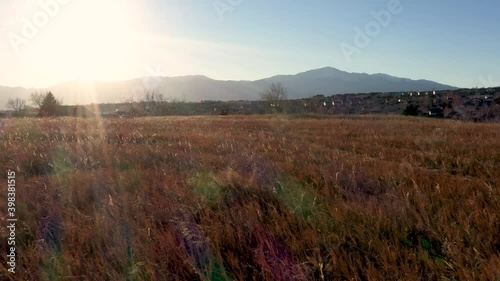 Sunset flight over grass field towards houses Pikes Peak Colorado 4K