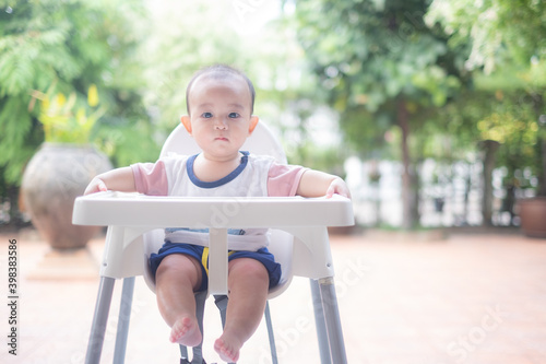 Asian infant Baby is sitting on the baby's chair preparing for the meal in the garden