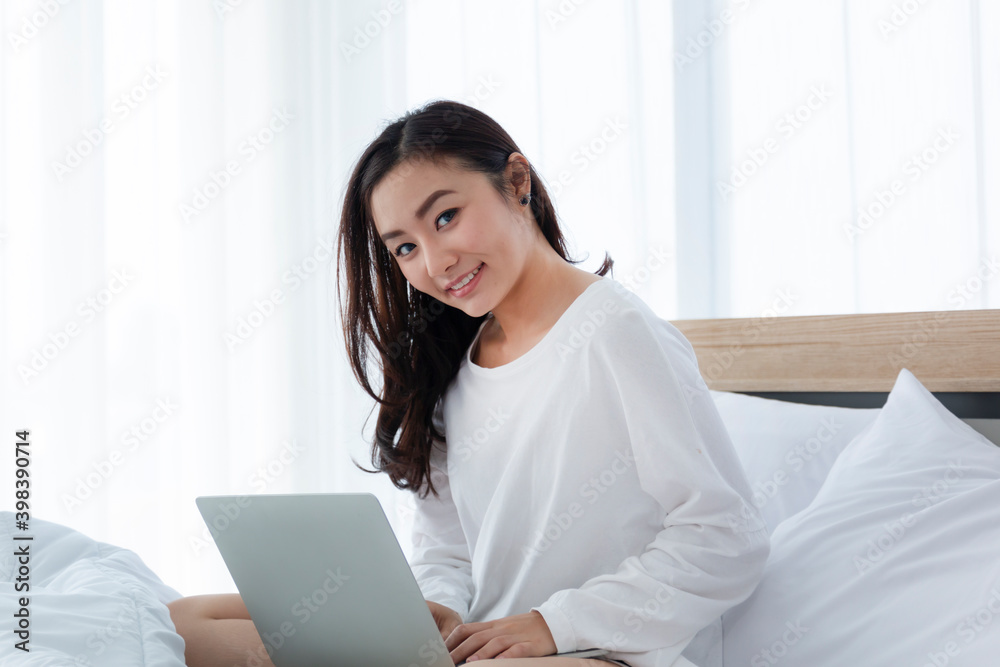 Happy casual beautiful woman working on a laptop sitting on the bed at home. Teen girl school student watch video online webinar learning on laptop sit on bed, distance e-learning course. Happy casual beautiful woman working on a laptop sitting on the bed at home. Teen girl school student watch video online webinar learning on laptop sit on bed, distance e-learning course.