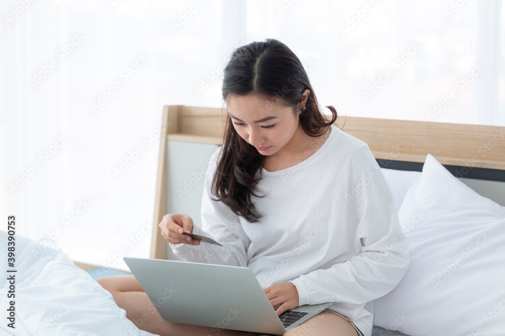 Woman sitting on the bed, shopping online with notebook. Happy casual beautiful woman working on a laptop sitting on the bed at home. Woman sitting on the bed, shopping online with notebook. Happy casual beautiful woman working on a laptop sitting on the bed at home.
