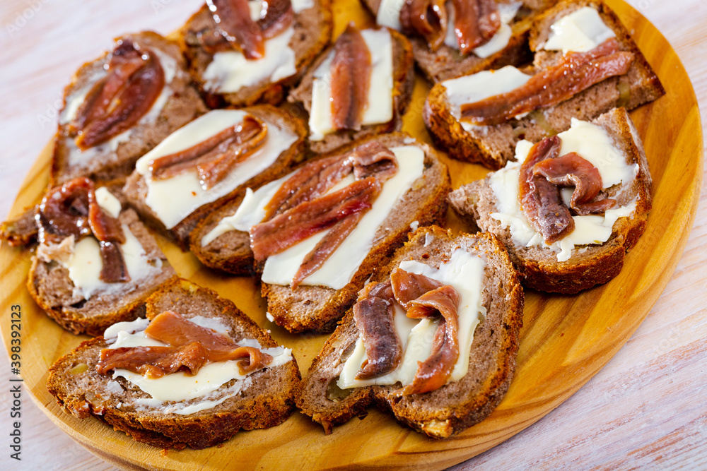 Tasty slices of bread with butter and salted anchovy fillets. Traditional spanish fish tapas