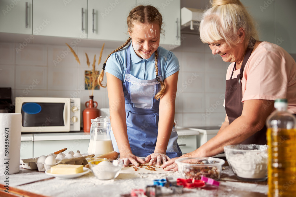 Elderly woman feeling happy while cooking together with her wonderful granddaughter