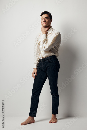 A man in full growth In a bright room and a white shirt, dark trousers model