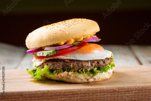 Side view on classic burger with egg on the wooden board