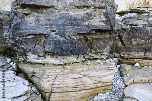 mountain textures of stones with interlayers of gypsum, colored quartz, clay, sand and other layers of various ores, with different textures, color and density, in gypsum ore quarry.