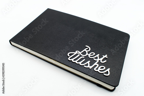 Black leather notebook with best wishes text on the cover 