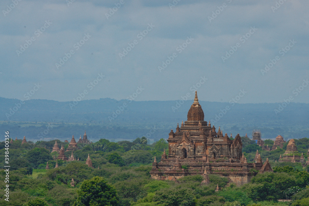 a large building with towers and a hill with trees and hills in the background