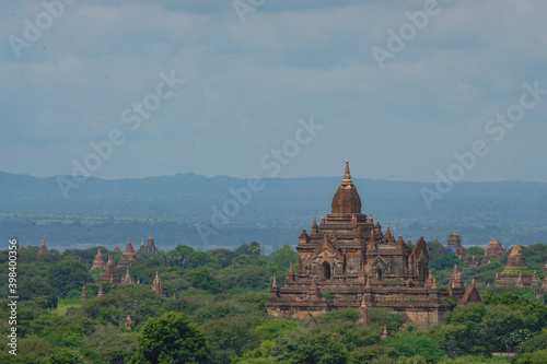 a large building with towers and a hill with trees and hills in the background