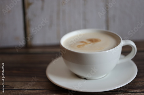 coffee in white cup with saucer on wooden table with wooden bottom