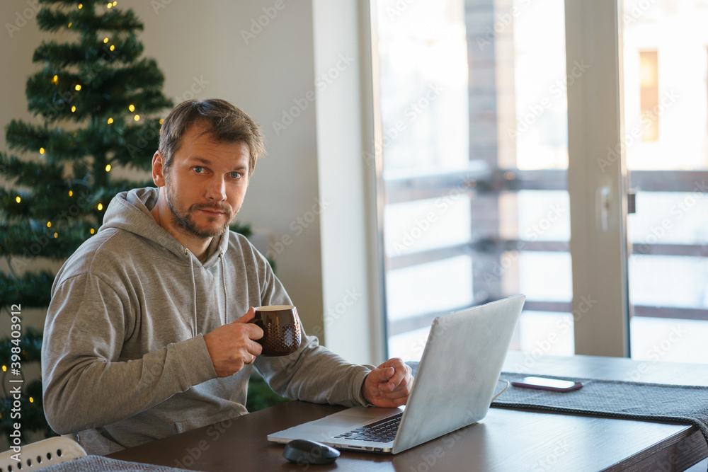 Young man works remotely from home while sitting at a table. Young man works remotely from home while sitting at a table.