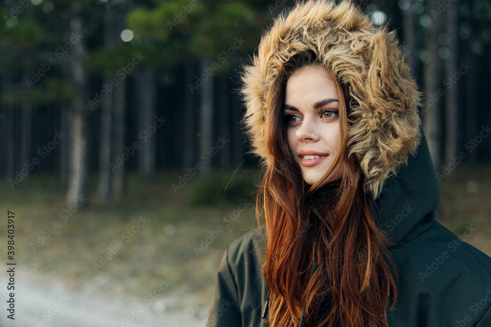 Woman in a jacket with a hood cool nature on the background of trees Woman in a jacket with a hood cool nature on the background of trees