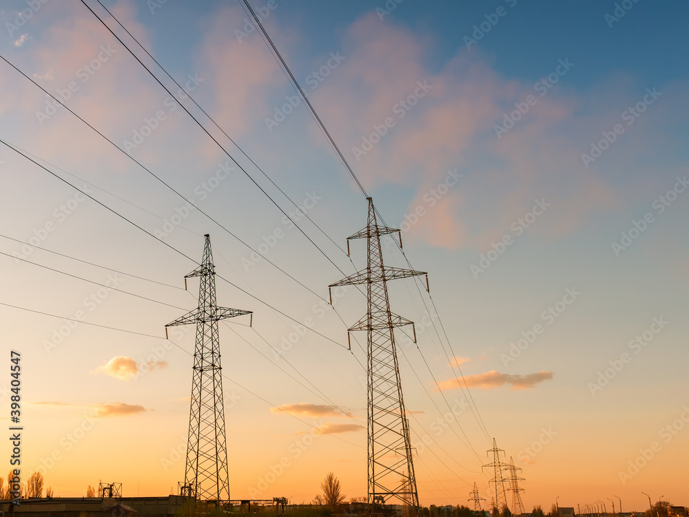 High-voltage power lines at sunset or sunrise. High voltage electric transmission tower