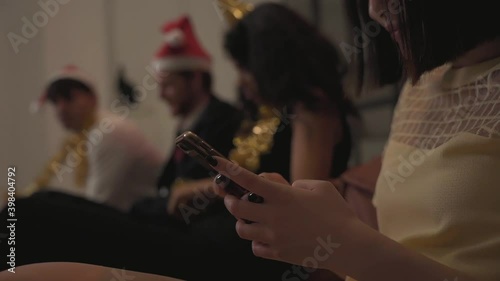Close-up. Woman hands with phone. People get bored at New Year's Eve party. Christmas at home.