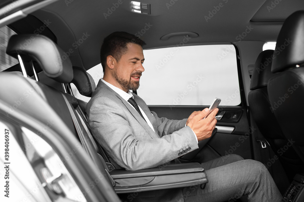 Successful businessman with mobile phone in modern car