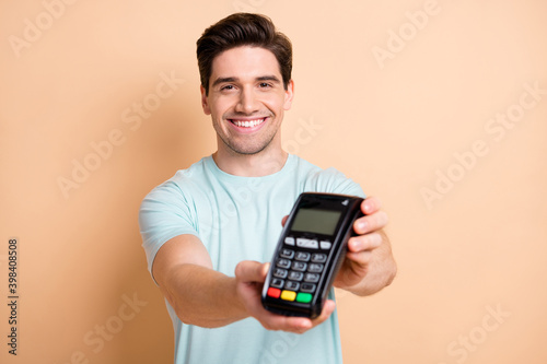 Close-up portrait of nice cheerful guy using giving you terminal fast safe transaction isolated over beige pastel color background photo