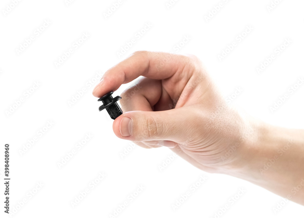 Hand holding black plastic clip for the car. Close up. Isolated on a white background Hand holding black plastic clip for the car. Close up. Isolated on a white background