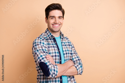 Profile side view portrait of attractive groomed cheerful guy folded arms isolated over beige pastel color background