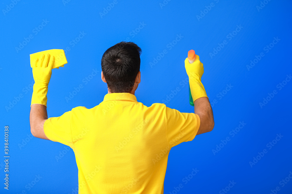 Young man with cleaning supplies on color background Young man with cleaning supplies on color background