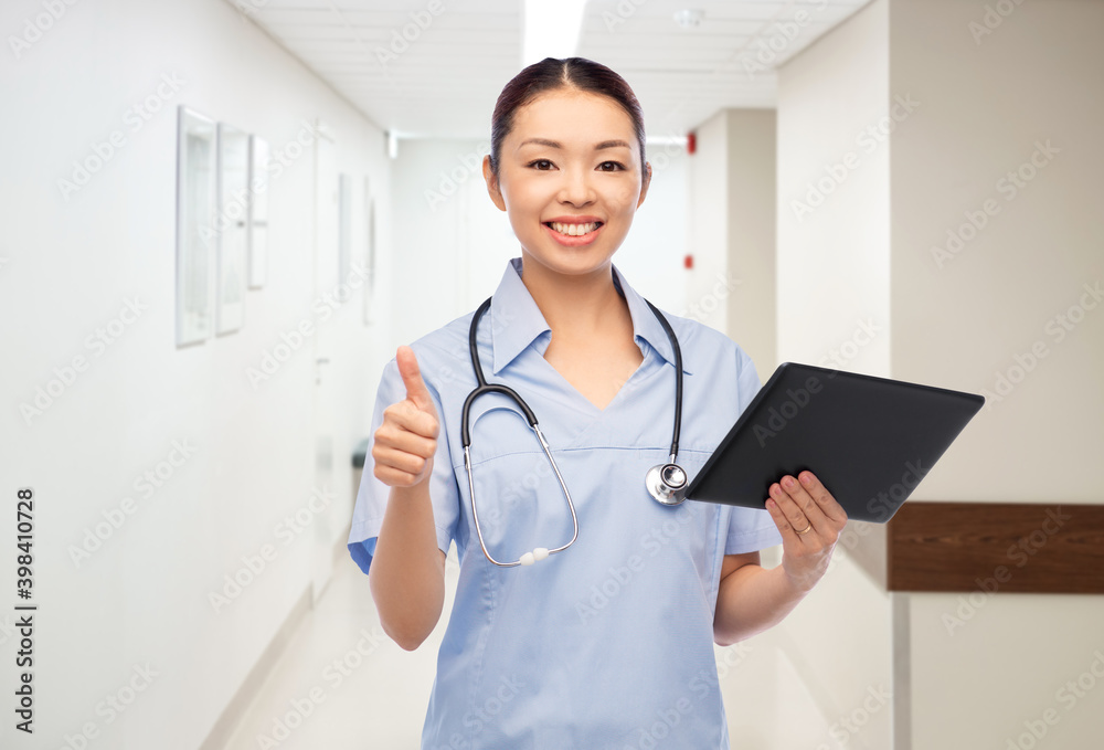 medicine, profession and healthcare concept - happy smiling asian female doctor or nurse with tablet pc computer and stethoscope showing thumbs up over hospital background medicine, profession and healthcare concept - happy smiling asian female doctor or nurse with tablet pc computer and stethoscope showing thumbs up over hospital background
