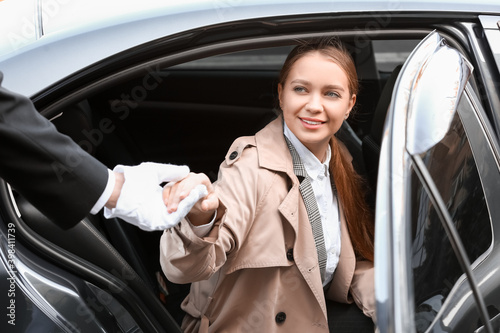 Chauffeur helping businesswoman to get out of car