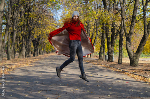 Young beautiful girl in red raincoat in autumn in the Park