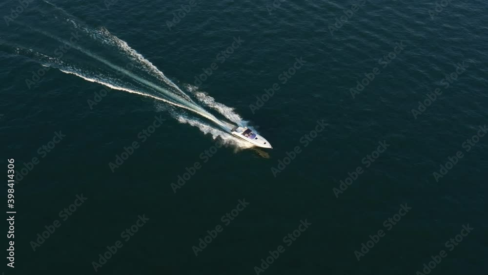 Large speed boat moving at high speed side view. Drone view of a boat the blue clear waters at sunset. The boat is white color. Top view of a boat sailing to the blue sea. Large speed boat moving at high speed side view. Drone view of a boat the blue clear waters at sunset. The boat is white color. Top view of a boat sailing to the blue sea.