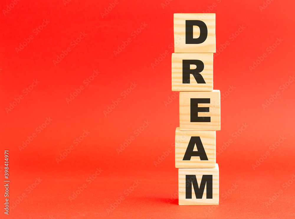 Wooden cubes with word DREAM. Wooden cubes on a red background. Free space on the left. Wooden cubes with word DREAM. Wooden cubes on a red background. Free space on the left.