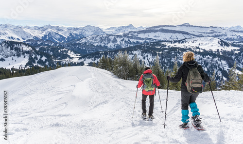 Senior couple is snowshoe hiking in alpine snow winter mountains. Allgau, Bavaria, Germany. © Drepicter