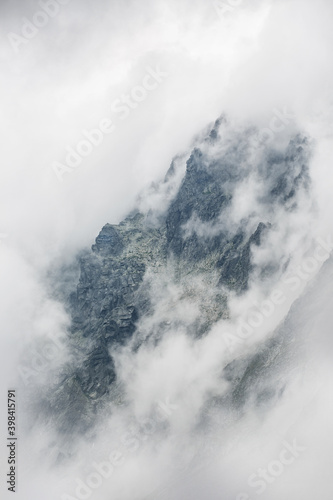 mystical photo of rough rocky mountains surrounded by a white blanket of clouds