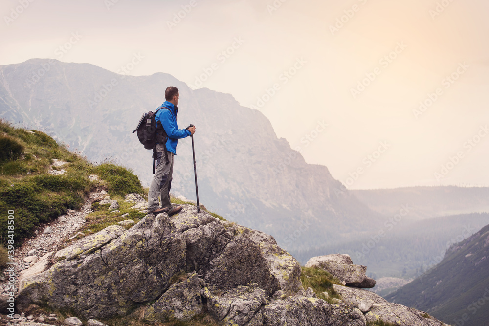 Hiker with backpack standing on top of a mountain