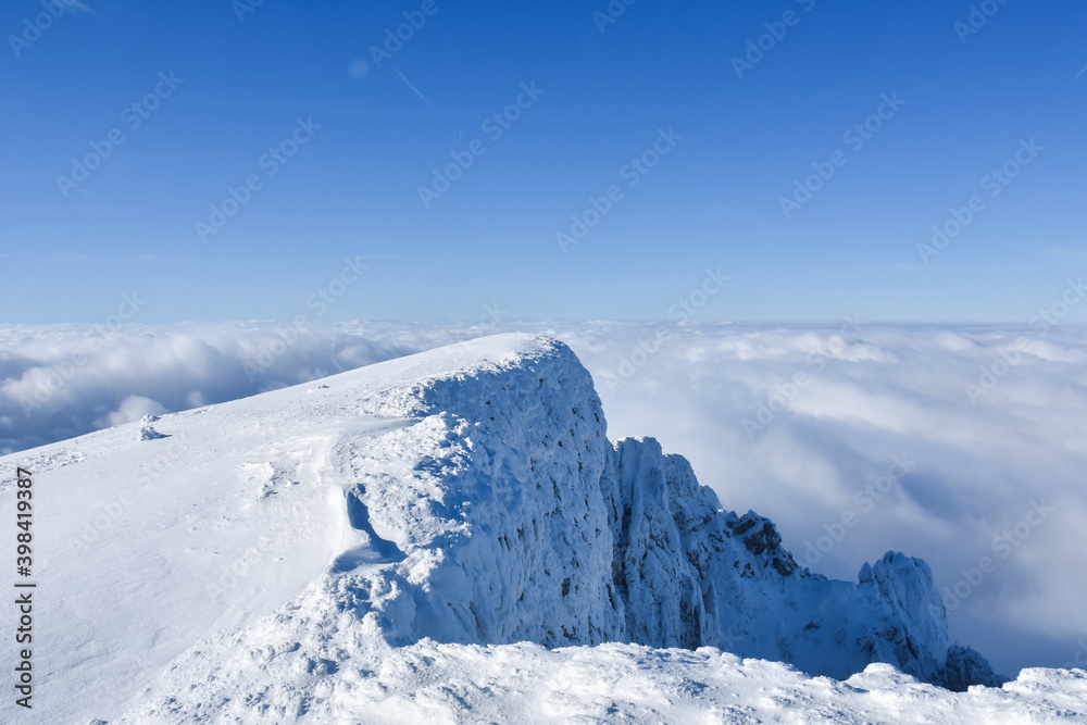 Obraz premium Winter mountain. Snowy peak high above the clouds. Show and clouds on Dry Mountain, Serbia