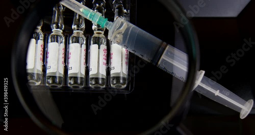 syringe with vaccine injection under a magnifying glass study video 4k