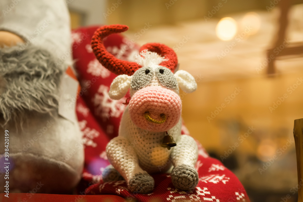 Bull cow is a symbol of 2021 according to the Eastern calendar. Handmade soft knitted toy on a New Year's bedspread