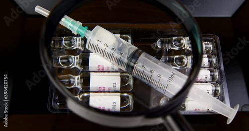 syringe with vaccine injection under a magnifying glass study video 4k