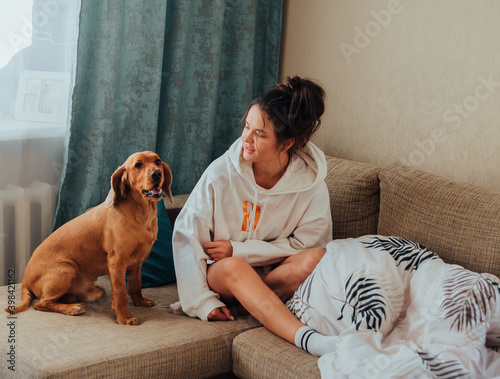 The girl looks at the dog that jumped on the sofa